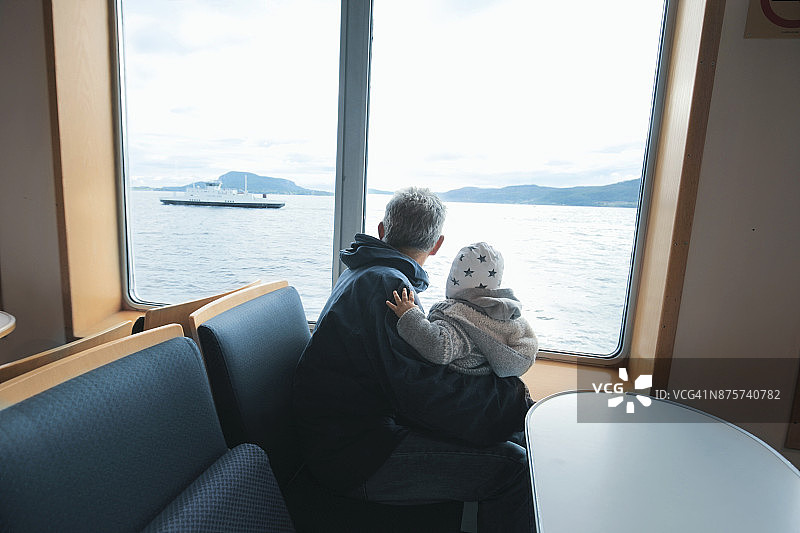 祖父和孙子在渡轮上看海洋和船图片素材