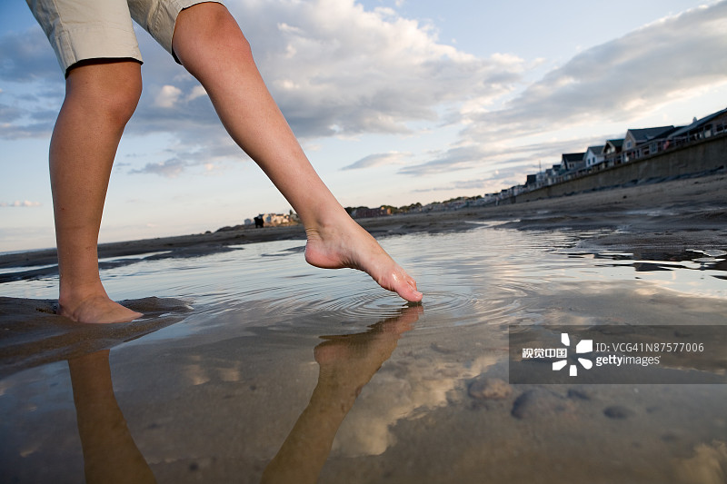 女人摸着脚趾在海滩上的潮池里图片素材