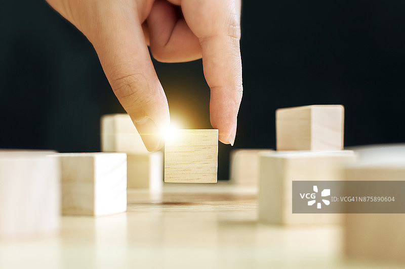 男性从众多木块中挑选一个，选择独特商业理念图片素材