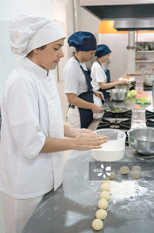 女厨师揉捏面团做披萨，表情严肃图片素材