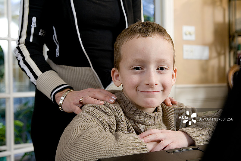 男孩坐在地上，母亲在他身后图片素材