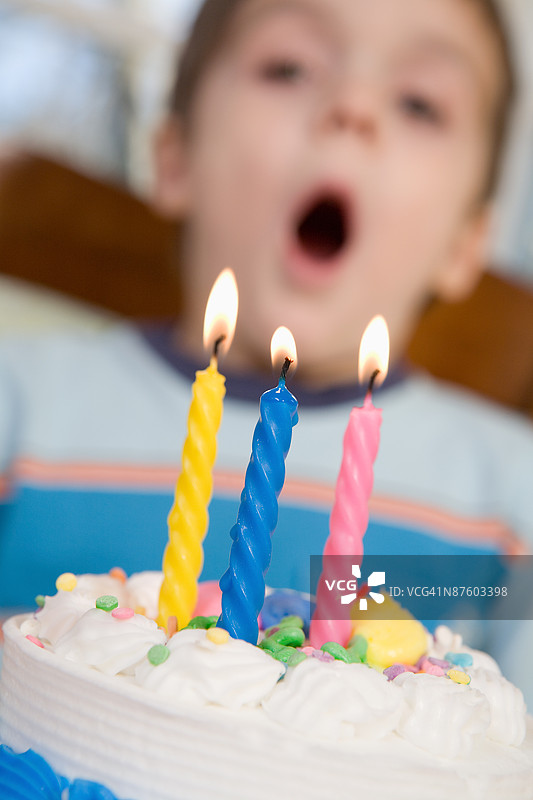 男孩在蛋糕上吹灭蜡烛图片素材