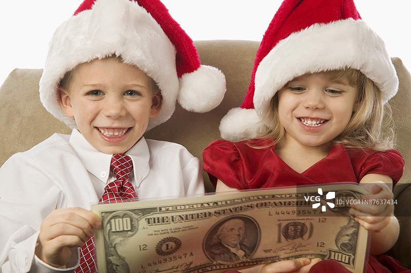 戴着圣诞老人帽的孩子们手里拿着钱图片素材