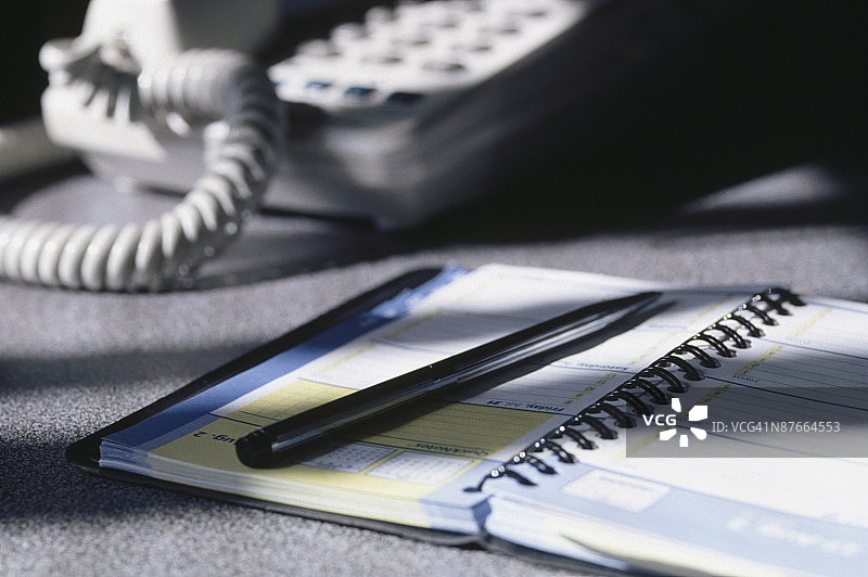 电话旁的记事本上的笔图片素材