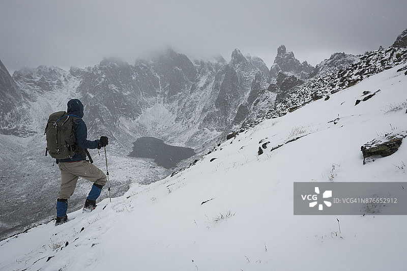 雪暴中，徒步者在育空地区墓碑领地公园的山脊上俯瞰巨石山和双子湖图片素材