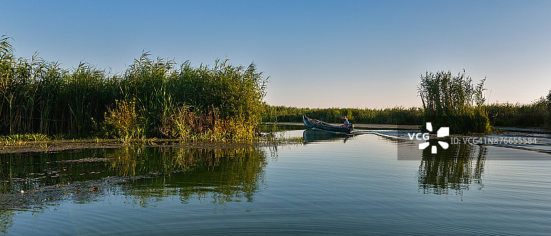 一位渔民驾驶着他的船穿过多瑙河三角洲图片素材