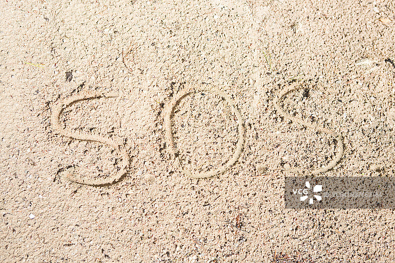 沙滩上用沙子书写的SOS图片素材