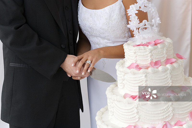 新娘和新郎握刀切结婚蛋糕的特写图片素材