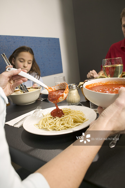 女人在意大利面上倒番茄酱图片素材