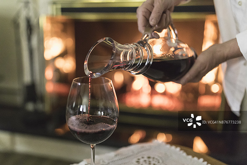 手拿玻璃醒酒器，往杯中倒红酒的女子图片素材