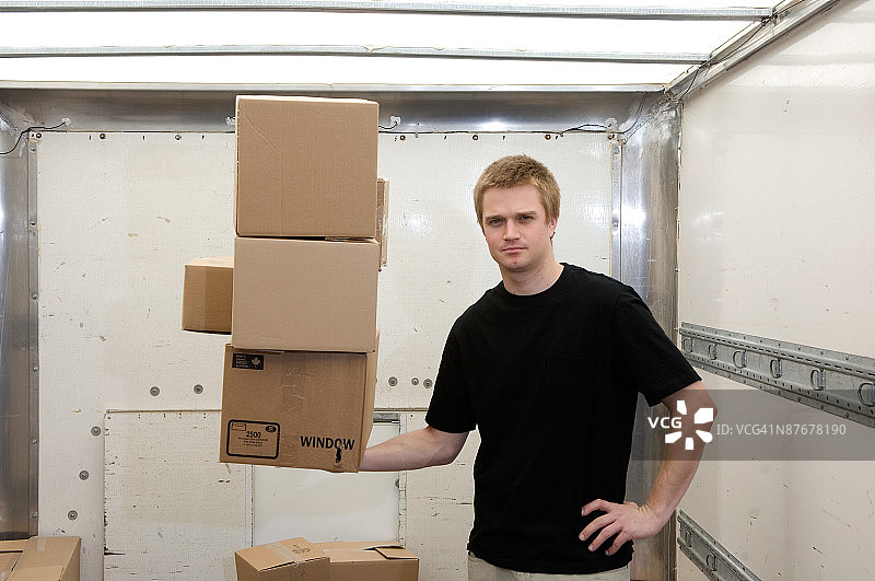 在卡车上单手平衡箱子的男人图片素材