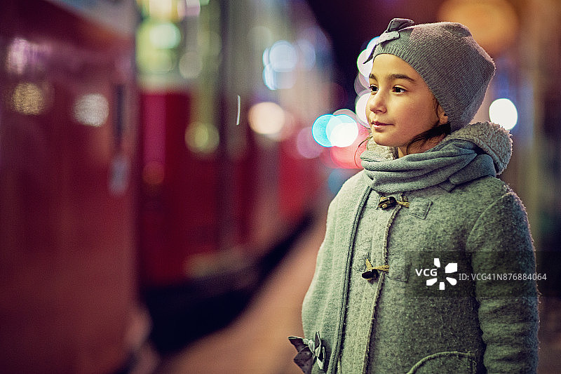 悲伤的小女孩站在夜晚的电车站图片素材
