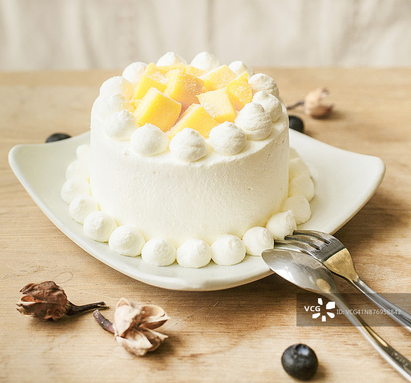 桌上白盘里的水果奶油蛋糕图片素材