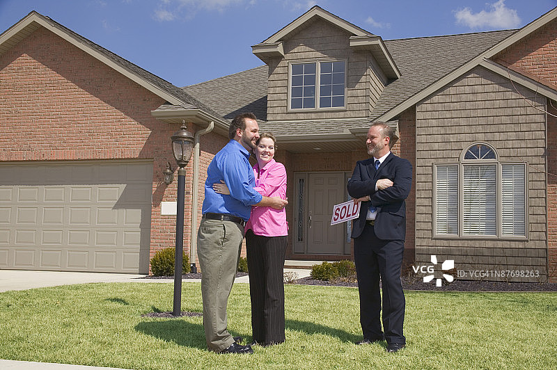 商人站在房子前，手持已售标志图片素材