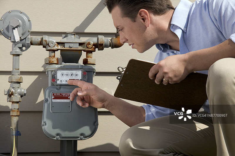 手持夹板的男子在检查仪表图片素材