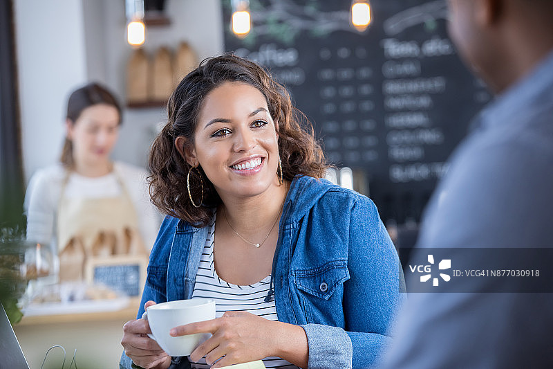在咖啡店偶遇老朋友的年轻女人图片素材