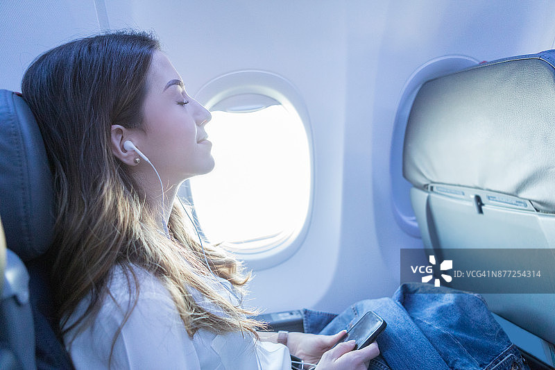 年轻女子在空中旅行时听着音乐休息图片素材