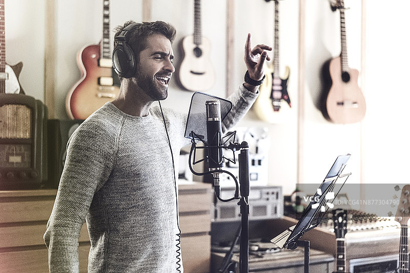 男子在录音棚里对着麦克风唱歌图片素材
