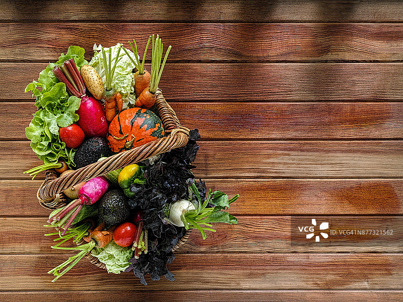 木质桌面上的柳条筐新鲜蔬菜沙拉图片素材