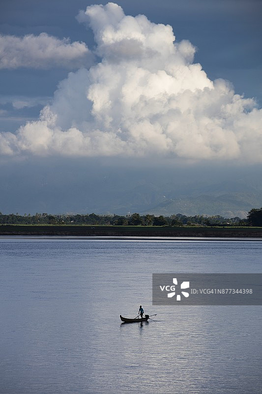 缅甸实皆省敏贡附近伊洛瓦底江上的渔船和远处的巨大白云图片素材