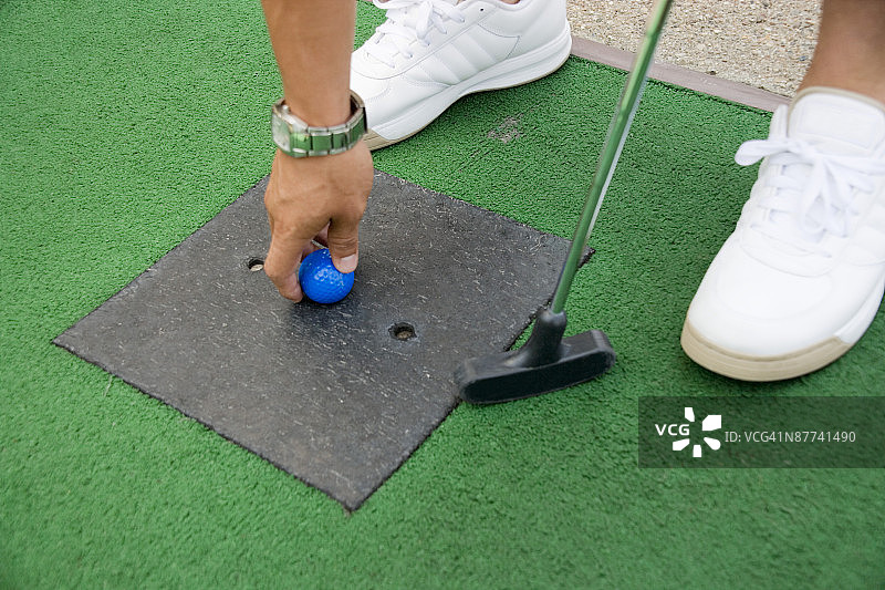 在迷你高尔夫球场上准备推杆的人的特写图片素材