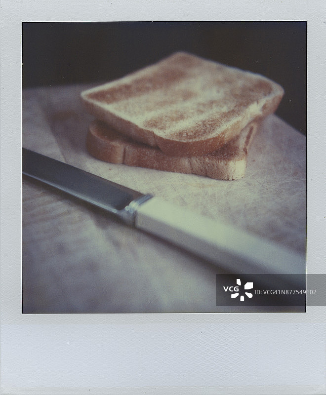 木制砧板上的吐司和刀的宝丽来照片图片素材