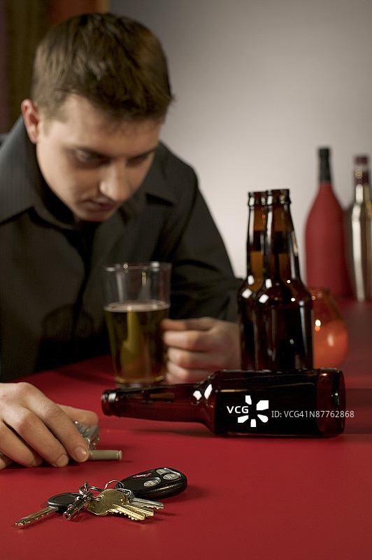 在酒吧里拿着钥匙和手机的醉汉图片素材