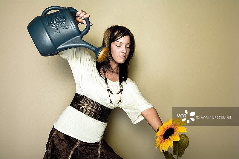 女人在工作室拍摄中浇灌向日葵图片素材