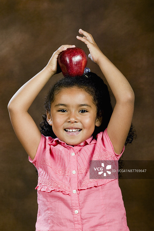 头上放着苹果的女孩图片素材