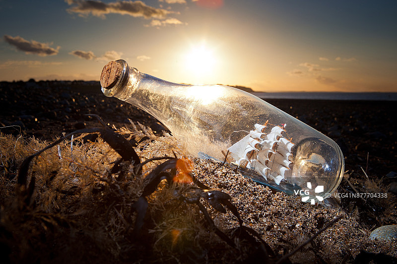 日落时分沙滩上的瓶中船图片素材