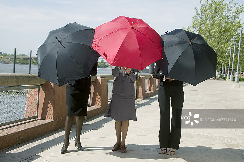 在户外躲在雨伞后的商务女性图片素材