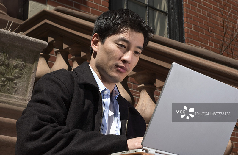 楼梯上的男子使用笔记本电脑图片素材