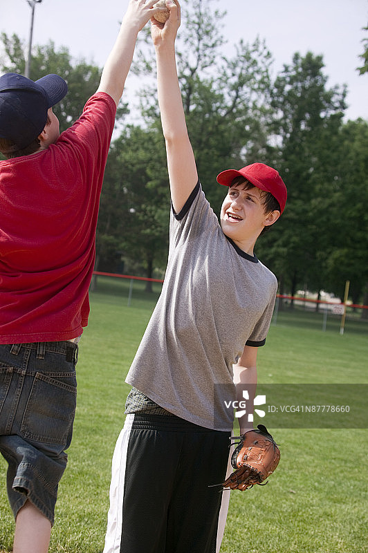棒球比赛中，一垒手将球伸出，使跳跃的跑垒员无法够到图片素材