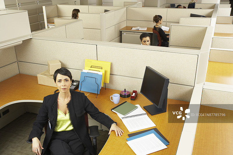 无聊的女商人在办公室的桌子前坐着图片素材