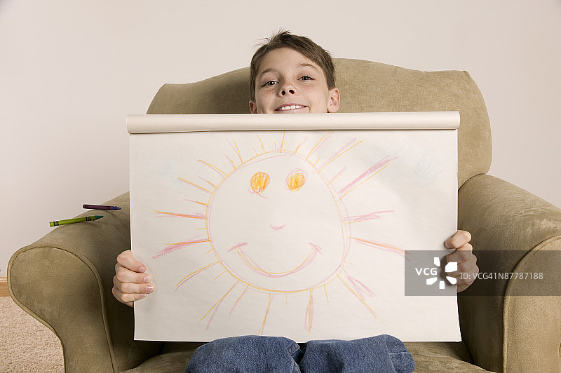 抱着微笑太阳画作的小男孩图片素材