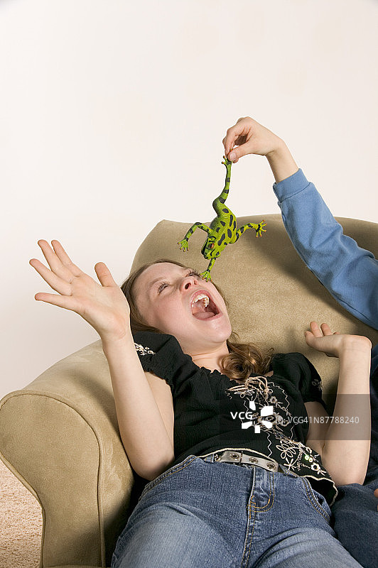 男孩用玩具青蛙吓唬女孩图片素材