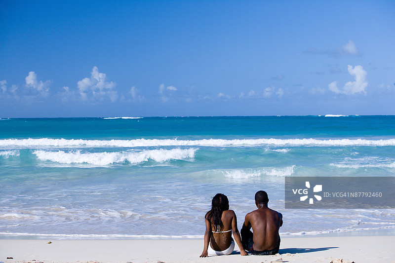在多米尼加共和国的海滩上坐着的一对情侣图片素材