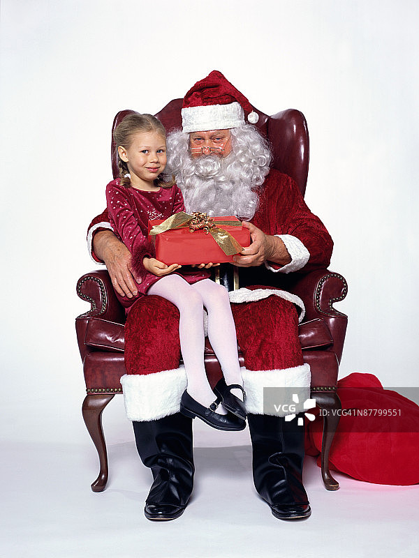 圣诞老人给坐在他腿上的小女孩送礼物图片素材