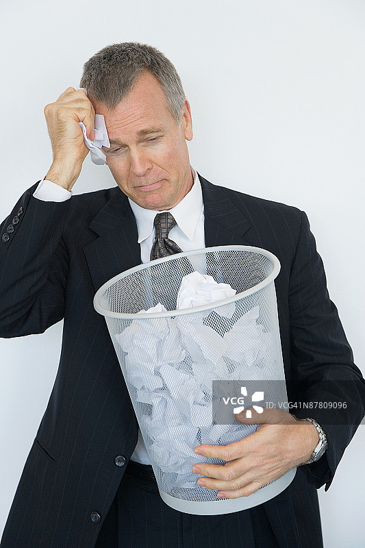 抱着废纸篓哭泣的沮丧商人图片素材