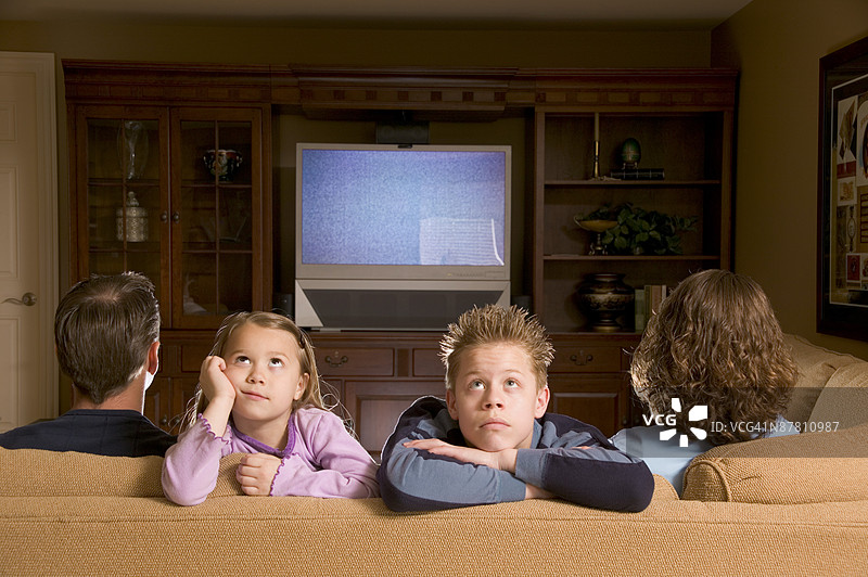 一家人正在看电视，孩子们背对着电视。图片素材