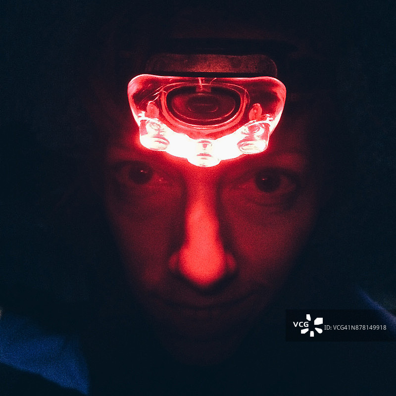 红色LED头灯照亮的女性面部图片素材