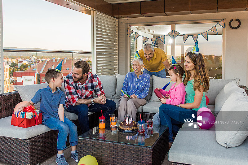 快乐的多代同堂家庭在顶层公寓露台上放松身心，举办生日派对图片素材