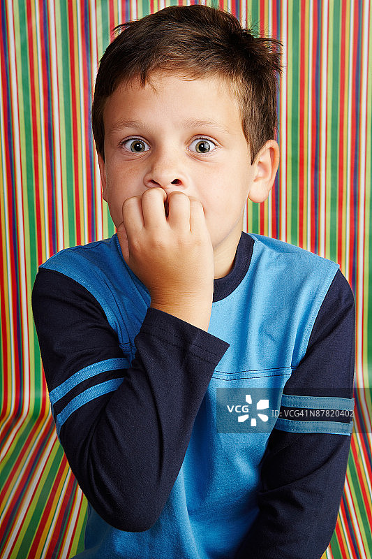 在条纹壁纸工作室里受惊的男孩图片素材