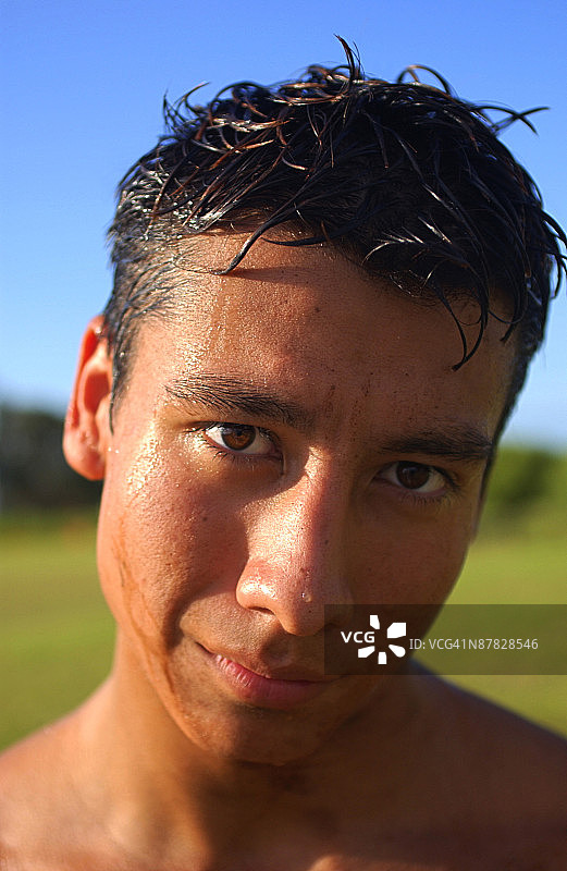 一位满头大汗的西班牙裔青少年男性的头部特写，看着镜头图片素材