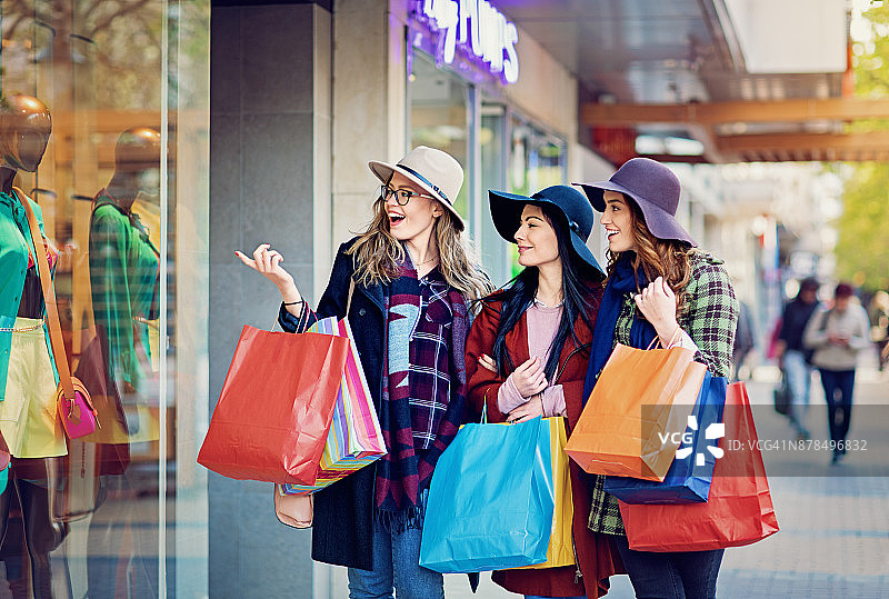 女友们在商店橱窗前购物图片素材