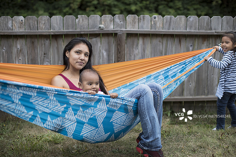 居家，美洲原住民母亲在后院吊床上和孩子们玩耍图片素材