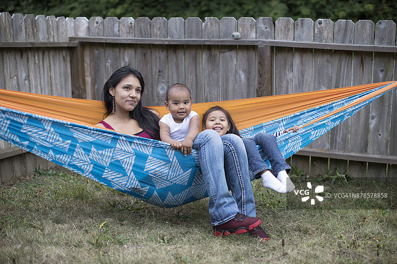 年轻美洲原住民母亲与孩子在吊床上玩耍图片素材