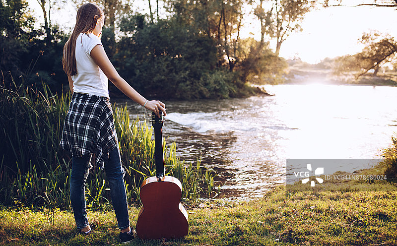 在自然中抱着吉他的年轻女人图片素材