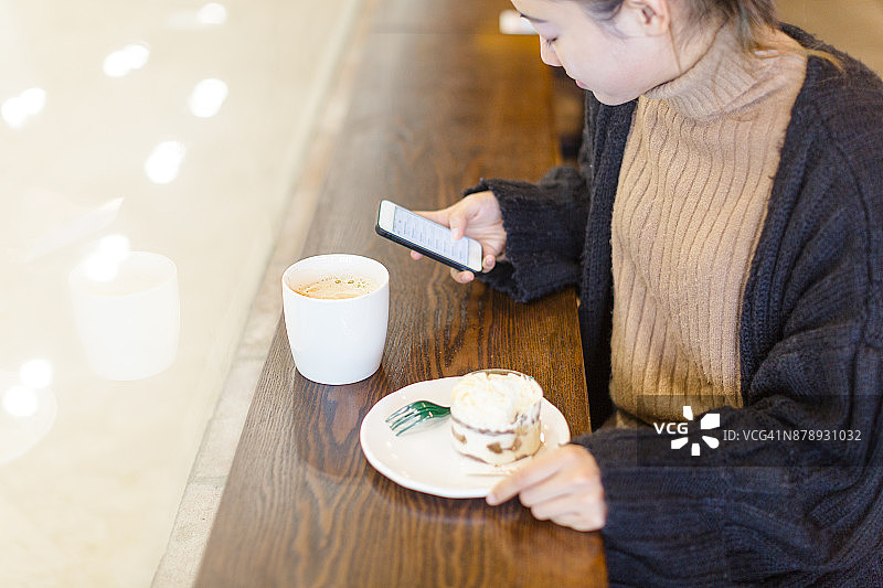 女人在咖啡馆用手机喝咖啡吃甜点图片素材