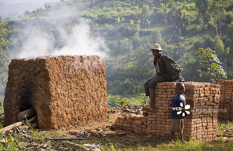 在非洲布隆迪 Cibitoke Masango 的雨林中，男人和男孩在砖堆和砖窑旁图片素材